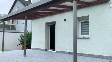 Überdachte Terrasse mit Metallstützen an Wohnhaus